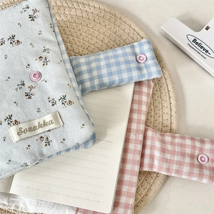 Detail of floral and checkered fabric notebook covers with snap buttons on a straw mat