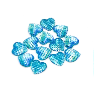 Macro detail of blue heart-shaped fish scale resin cabochons with iridescent shimmer