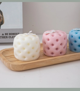 Macro view of geometric scented candles with quilted texture on a wooden tray