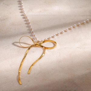 Elegant 18k gold plated stainless steel necklace with white pearls and a bow pendant