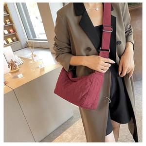 Detail of burgundy quilted tote bag with diamond pattern and matching wide shoulder strap