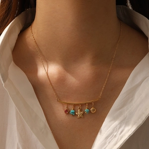 Detail of 18K gold-plated necklace with sea shell, starfish, and turquoise charms on neck