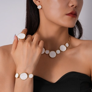 Parure de bijoux dorés géométriques avec émail blanc portée par un mannequin