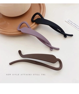 Close-up of matte twisting hair clips in black, purple and brown on a ceramic tray