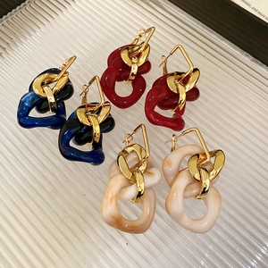 Close-up of geometric resin chain earrings in blue, red, and cream marble with gold accents