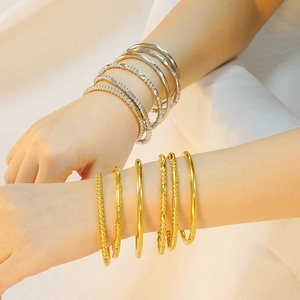 Stack of gold and silver stainless steel beaded and bamboo texture bangles on wrist