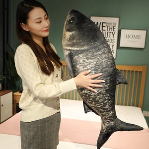 Realistic large fish plush pillow with detailed scale texture shown in a bedroom setting
