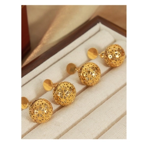 Detail of gold geometric hollow ball earrings with zircons in a jewelry box
