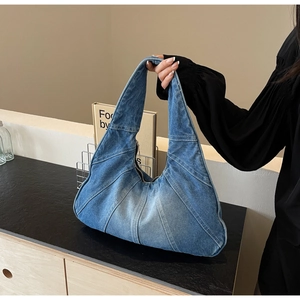 Détail du sac à bandoulière en denim bleu avec texture patchwork et fermeture éclair