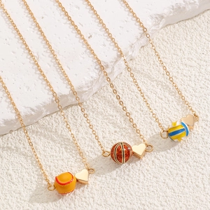 Détail de colliers dorés sur le thème du sport avec charms coeur sur pierre blanche