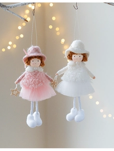 Detail of plush angel dolls with mesh skirts hanging from a branch with warm lights