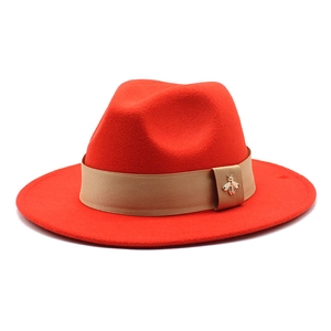 Detailed shot of red wool felt hat with khaki ribbon and golden bee accessory
