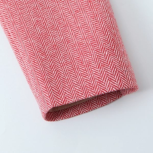 Detailed close-up of red and white herringbone wool fabric on a blazer sleeve cuff