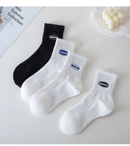 Flat lay of white and black cotton rib crew socks with blue MOMOGN logo embroidery