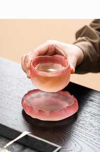 Detail of pink crystal glass tea cup with textured flower-shaped rim and saucer