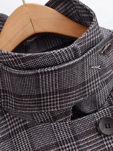 Detailed close-up of checkered pattern fabric and dark buttons on a plaid jacket