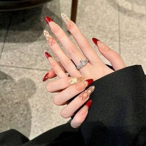 Deep red press-on nails with cat eye patterns and golden glitter for elegant festive look