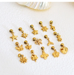Collection of golden stainless steel charms like starfish and hearts on white fabric