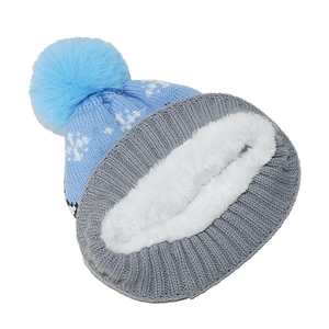 Detail of blue knitted winter hat with pom-pom and thick white fleece-lined neck warmer