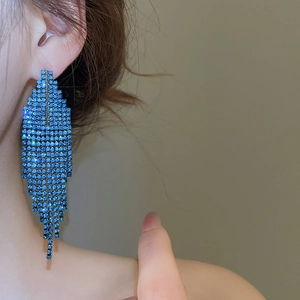 Détail de boucles d'oreilles à longs pompons bleus montrant des franges sur le mannequin