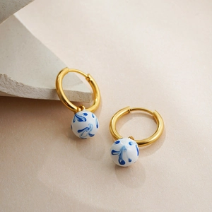 Detail of 18K gold hoop earrings with blue and white porcelain beads on stone
