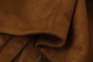Detailed macro view of brown suede fabric texture with precision stitching on jacket