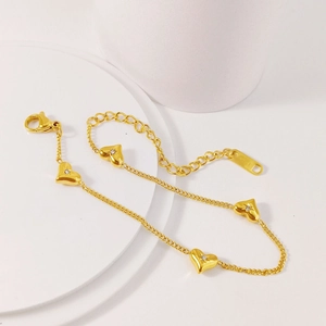 Detail of gold heart charms with zircon inlay and lobster clasp on fine chain bracelet