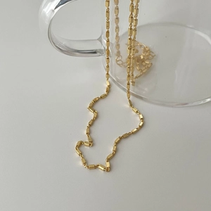 Detail of 925 sterling silver golden square link chain draped over a glass