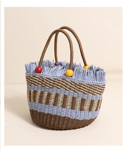 Detail of handwoven straw bag with colorful wood beads and blue striped fringe edges
