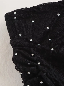 Détail du tissu en dentelle noire avec strass argentés et texture de tricot complexe