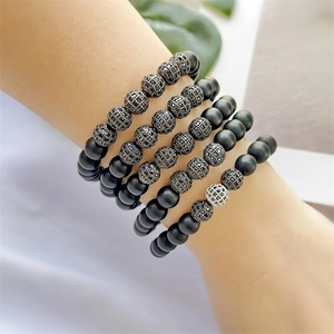 Detail von mattschwarzen Perlenarmbändern mit Mikro-Zirkonia-Anhängern am Handgelenk
