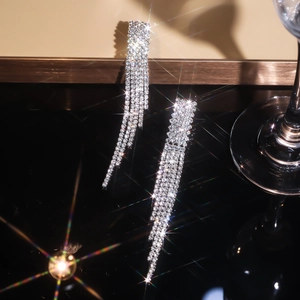 Macro shot of silver crystal long tassel earrings with sparkling rhinestones and starburst light
