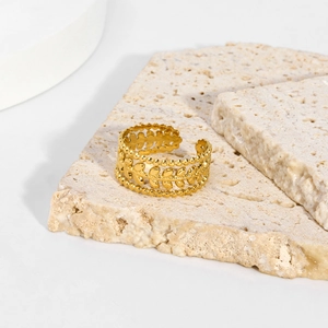 Macro view of vintage 18K gold leaf镂空 texture and beaded edges on a stainless steel ring