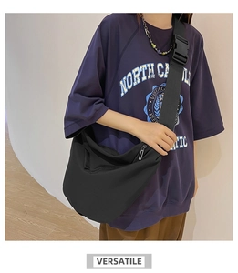 Detailed view of black nylon dumpling crossbody bag with adjustable wide strap on model