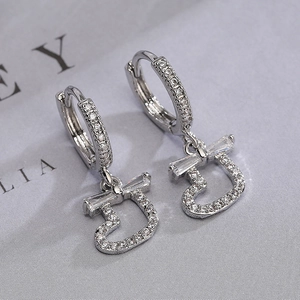 Silver hoop earrings with sparkling zircon letter J pendant on textured gray background
