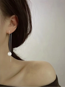 Dettaglio orecchini lunghi in argento S925 con nappa e perla bianca indossati da modella