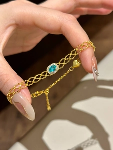 Macro shot of French vintage gold bracelet with green emerald stone and heart charm
