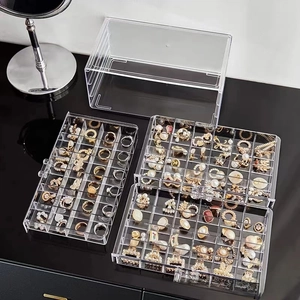 Detailed top view of a transparent acrylic jewelry organizer box with three slide-out trays