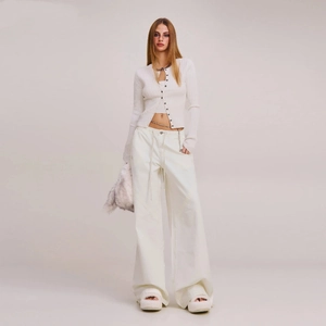 Full body view of a white slim knit cardigan with metal chain wide leg trousers