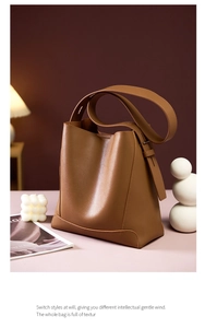 Detail einer braunen Leder-Eimertasche mit verstellbarem Gurt in stilvoller Umgebung