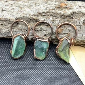 Dettaglio di ciondoli in fluorite verde grezza avvolti a mano con filo di rame vintage