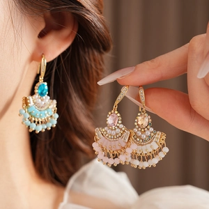 Détail de boucles d'oreilles éventail vintage en or avec glands en zircon sur un mannequin