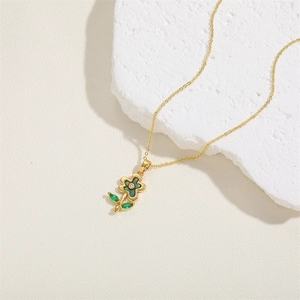 Close-up of a gold flower necklace with green shell petals and zircon on white stone