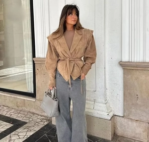 Close-up of brown suede biker jacket with tie-waist detail and grey wide-leg jeans