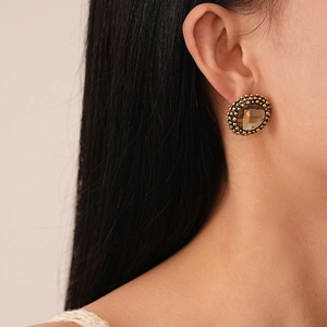 Close-up of vintage flower earrings with amber crystals worn by a female model