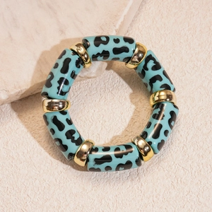 Detail of turquoise leopard print acrylic bracelet with gold textured spacers and elastic cord