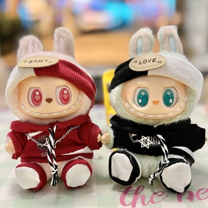 Close-up of plush dolls in knitted bunny hoodies and star necklaces on a soft surface