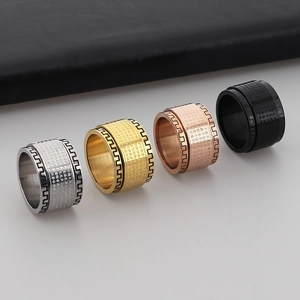 Detailed close-up of four rotating stainless steel mantra rings in silver, gold, and black