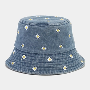 Dettaglio del ricamo a margherita bianca sul cappello alla pescatora in denim azzurro