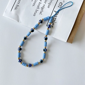 Close-up of handmade blue beaded phone strap with evil eye charms and golden accents